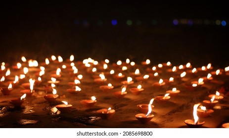 Close up shot of Dev Deepawali 2021 festival, Earthen lamps lit on the stairs leading to the Ganges with selective focus. 
Thousands of diyas (oil lamps) are lined up on the stairs near Ganges.