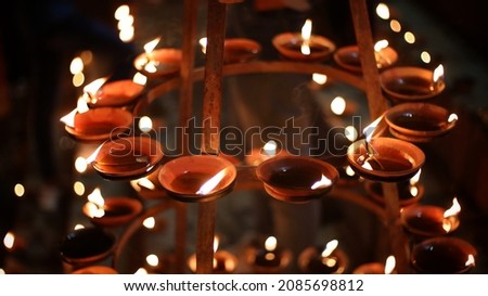 Close up shot of Dev Deepawali 2021 festival, Earthen lamps lit on the stairs leading to the Ganges with selective focus. 
Thousands of diyas (oil lamps) are lined up on the stairs near Ganges.
