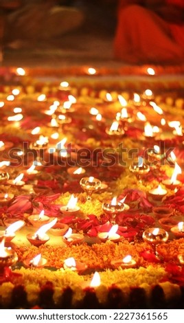 Close up shot of Dev Deepawali 2022 festival, Earthen lamps lit on the stairs leading to the Ganges with selective focus. Thousands of diyas (oil lamps) are lined up on the stairs near Ganges.
