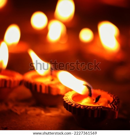 Close up shot of Dev Deepawali 2022 festival, Earthen lamps lit on the stairs leading to the Ganges with selective focus. Thousands of diyas (oil lamps) are lined up on the stairs near Ganges.
