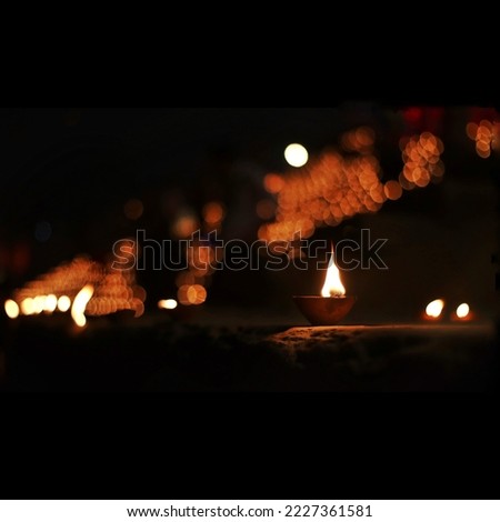 Close up shot of Dev Deepawali 2022 festival, Earthen lamps lit on the stairs leading to the Ganges with selective focus. Thousands of diyas (oil lamps) are lined up on the stairs near Ganges.
