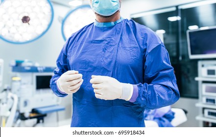 Close up shot of doctor wearing surgical gloves and scrubs in operation theater. Surgeon ready for operation in hospital. - Powered by Shutterstock