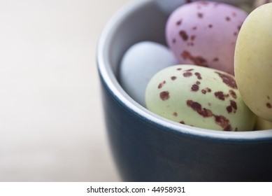 Close Up Shot Of An Egg Cup Filled With Easter Egg Sweets.  Background Provides Copy Space On Soft-focus Birchwood Table.