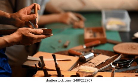 Close up shot of experienced craftsman in leather belt making process at his workshop - Powered by Shutterstock