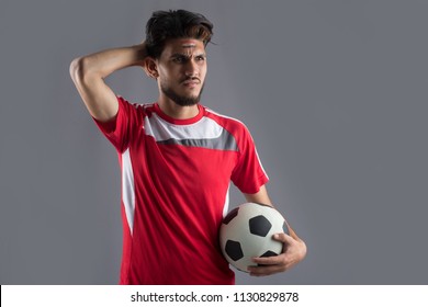 Close Shot Of Fan Is Disappointed Man With The Team Of His Country, With The Flag Of Egypt Makeup On His Face And A Red T-shirt, Putting His Hand In The Head And Holding A Ball.