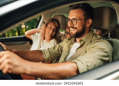 Close shot of father driving a car while the whole family of four is going on a weekend trip away from the city. Parents making a road trip with their daughters in their new car. Transport and safety. - Powered by Shutterstock