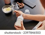 Close up shot of female hands checking temperature of prepared infant formula, copy space