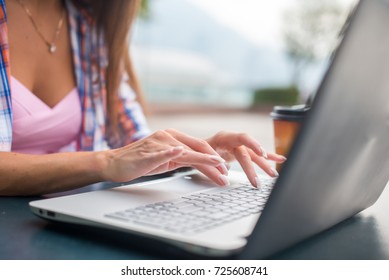 Close up shot of female hands typing on a laptop keyboard. Young woman studying and working in the park - Shutterstock ID 725608741