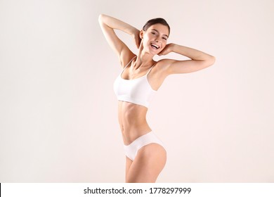 Close up shot of a fit woman in lingerie isolated on white background. Slim attractive female with flat belly in white underwear posing. Copy space for text.