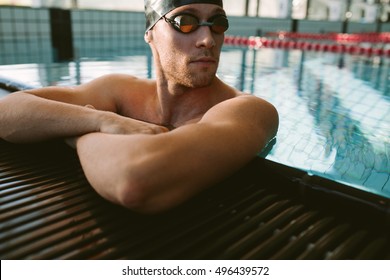 Close up shot of fit young man at the edge of swimming pool. Pro male swimmer relaxing at pool edge. - Powered by Shutterstock