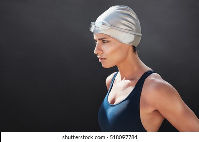 Close Up Shot Of Fit Young Woman In Swimming Costume Looking Away On Black Background. Female Swimmer Looking Focused Before Her Workout.