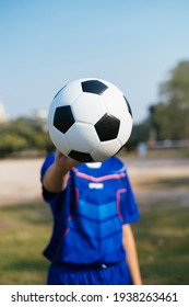 Close up shot of football in a boy's hand while he standing in a field.