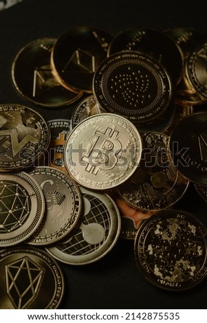 Close up shot of a golden Bitcoin in a stack, among other various digital cryptocurrencies .