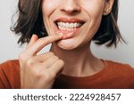 Close up shot of gum inflammation. Cropped shot of a young woman showing red bleeding gums isolated on a gray background. Dentistry, dental care