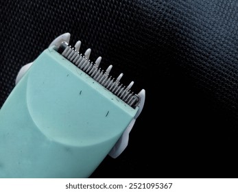 Close up shot of hair clipper blade covered with hair, green or turquoise hair clipper with black background - Powered by Shutterstock