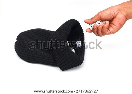 A close up shot of a hand holding multiple white dice with blue dots, dropping them into a black