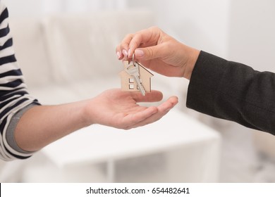 Close Up Shot Of Hands Giving Keys Of An Apartment. Woman Hand Passing Keys To New Owners.