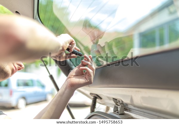 Close\
up shot hands of man removing old car window\
film