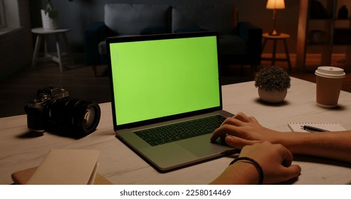 Close up shot of hands of a remote worker working on laptop computer with chroma key green screen, moving finger on trackpad - distance work, technology concept close up 