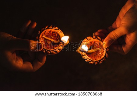 Close up shot of hands of two woman holding lit diya during Indian festival Diwali