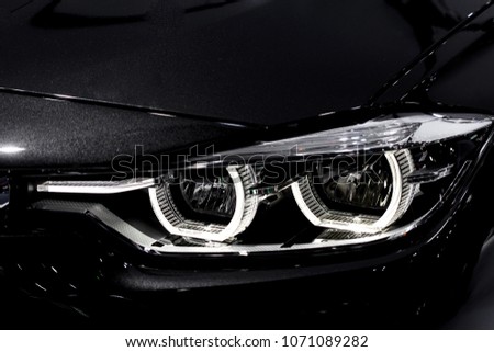 Close up shot of headlight in luxury 
black car background. Modern and expensive sport car concept