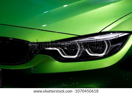 Close up shot of headlight in luxury 
green car background. Modern and expensive sport car concept