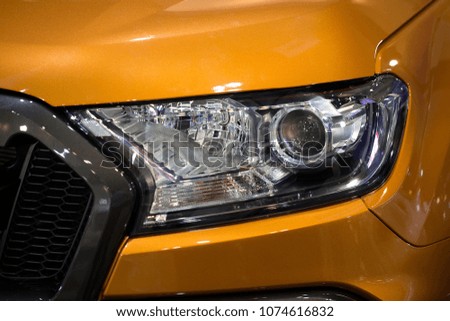 Close up shot of headlight in luxury 
orange car background. Modern and expensive sport car concept