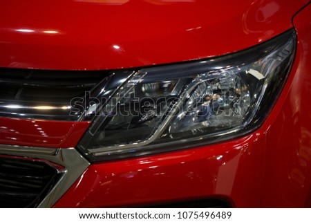 Close up shot of headlight in luxury 
red car background. Modern and expensive sport car concept