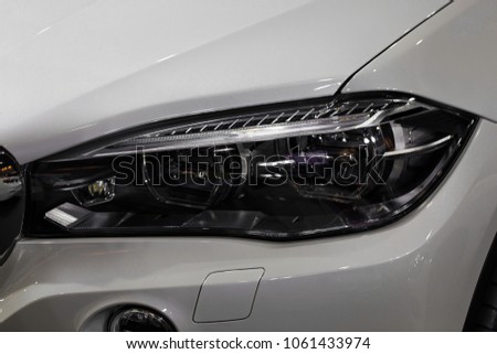 Close up shot of headlight in luxury 
 white car background. Modern and expensive sport car concept