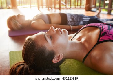 Close Up Shot Of Healthy Young Woman Lying On Floor. Young People Relaxing In Savasana Pose At Yoga Class.