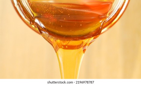 Close Up Shot Of Honey Pouring Out Of Glass Jar. Health And Beauty Product Sustainable Lifestyle Concept.