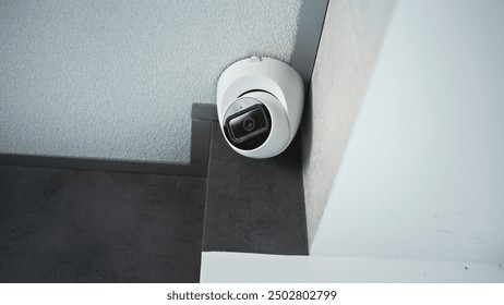 Close up shot of installed CCTV camera hanging on the ceiling in the room of the office building. Modern monitoring and tracking technologies. Security system, video surveillance and privacy concept.
