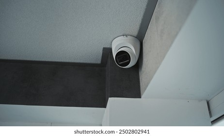 Close up shot of installed CCTV camera hanging on the ceiling in the room of the office building. Modern monitoring and tracking technologies. Security system, video surveillance and privacy concept.