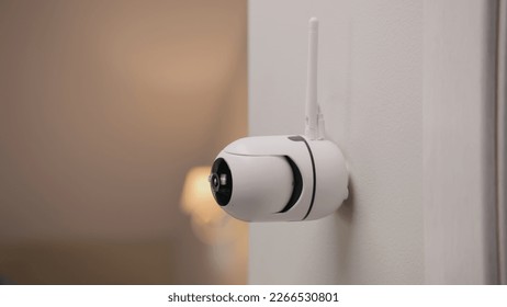 Close up shot of installed security camera on wall in modern apartment. CCTV camera with microphone and green indicator. Concept of monitoring system, surveillance and personal privacy.