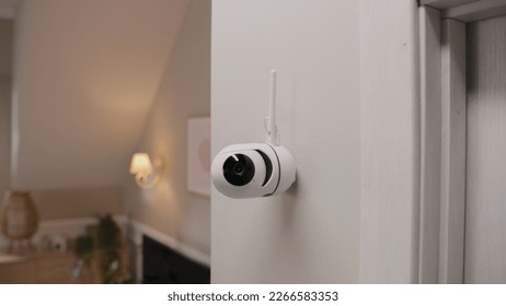 Close up shot of installed security camera on wall in modern apartment. CCTV camera with microphone and green indicator. Concept of monitoring system, surveillance and personal privacy.