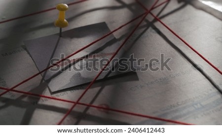 Close up shot of investigation board. Detective board with map of crime scene, pinned note with man face and red thread connecting clue proofs.