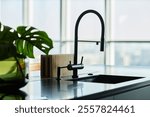 Close up shot of kitchen faucet silhouette mounted on black marble countertop in modern minimalist kitchen, copy space