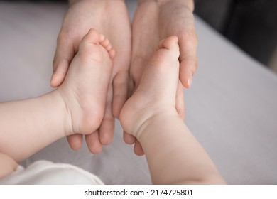 Close up shot loving mom palms holding feet, tiny toes of new born baby. Unrecognizable mother touches barefoot legs of 0-6 child, enjoy bonding, moments with infant feeling unconditional love concept - Shutterstock ID 2174725801