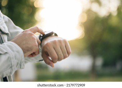 Close up shot of male's hand uses of wearable smart watch at outdoor in sunset. Smart watch. Smart watch on a man's hand outdoor. Man's hand touching a smartwatch. - Powered by Shutterstock