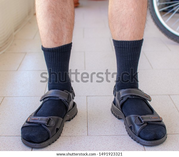 Close\
up shot of a man wearing black socks with\
sandals.