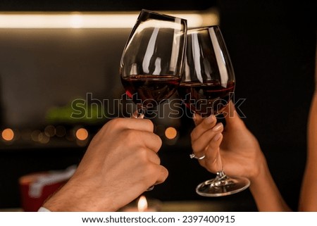Close up shot of man and woman toasting and drinking red wine from glasses on dinner. Alcohol drinks cropped image. Special event celebration, Valentine`s day, anniversary