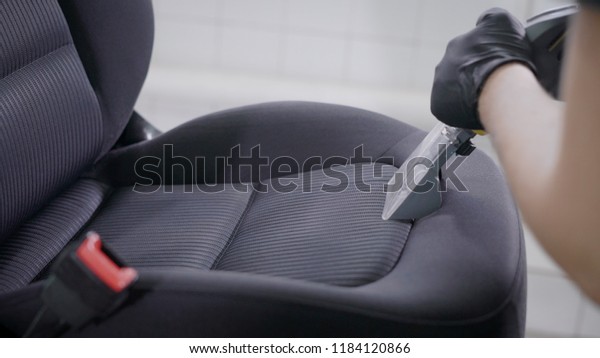 Close up shot of a master wet cleaning car seats\
indoor. Professional cleaning services. Man wet cleaning seat with\
a powerful vacuum\
cleaner.