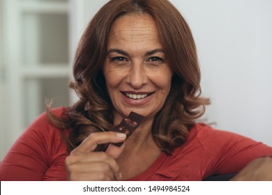 Close Up Shot Of Mature Woman Eating Chocolate In Her Home