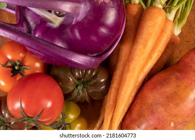 Close up shot of mixed vegetables on the kitchen bench. Super healthy food options in a variety of colours. Raw carrots, tomatoes and sweet potato. 