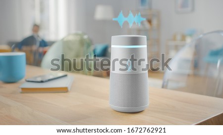 Close Up Shot of a Modern Silver Wireless Speaker Standing on a Table at Home with Voice Recording Hologram