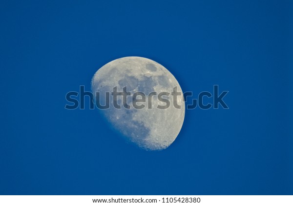 close up shot of moon surface in the early morning\
with blue sky