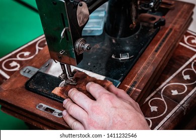 Close Up Shot Of An Old Vintage Sewing Machine. Traditional Handcraft, 19th Century Industrial Technology. Taylor Working And Stitching A Leather Patch. 