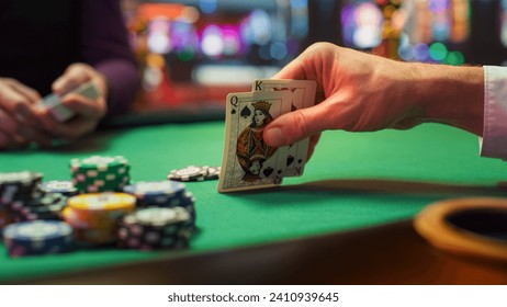 Close Up Shot On Hand Of Anonymous Poker Player Checking Playing Cards He Was Dealt. Professional High Stakes Gambler Making A Bet, Thinking Of Strategy, Counting Chips In Competitive Tournament.