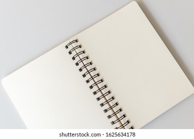 Close up shot of an open blank sketchbook placed on a light gray table.