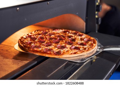 Close up shot of placing pizza to oven at pizzeria